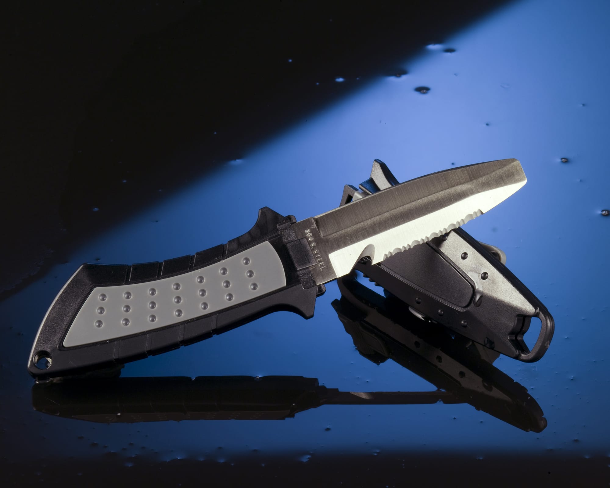 An unsheathed stainless steel diving knife with its case