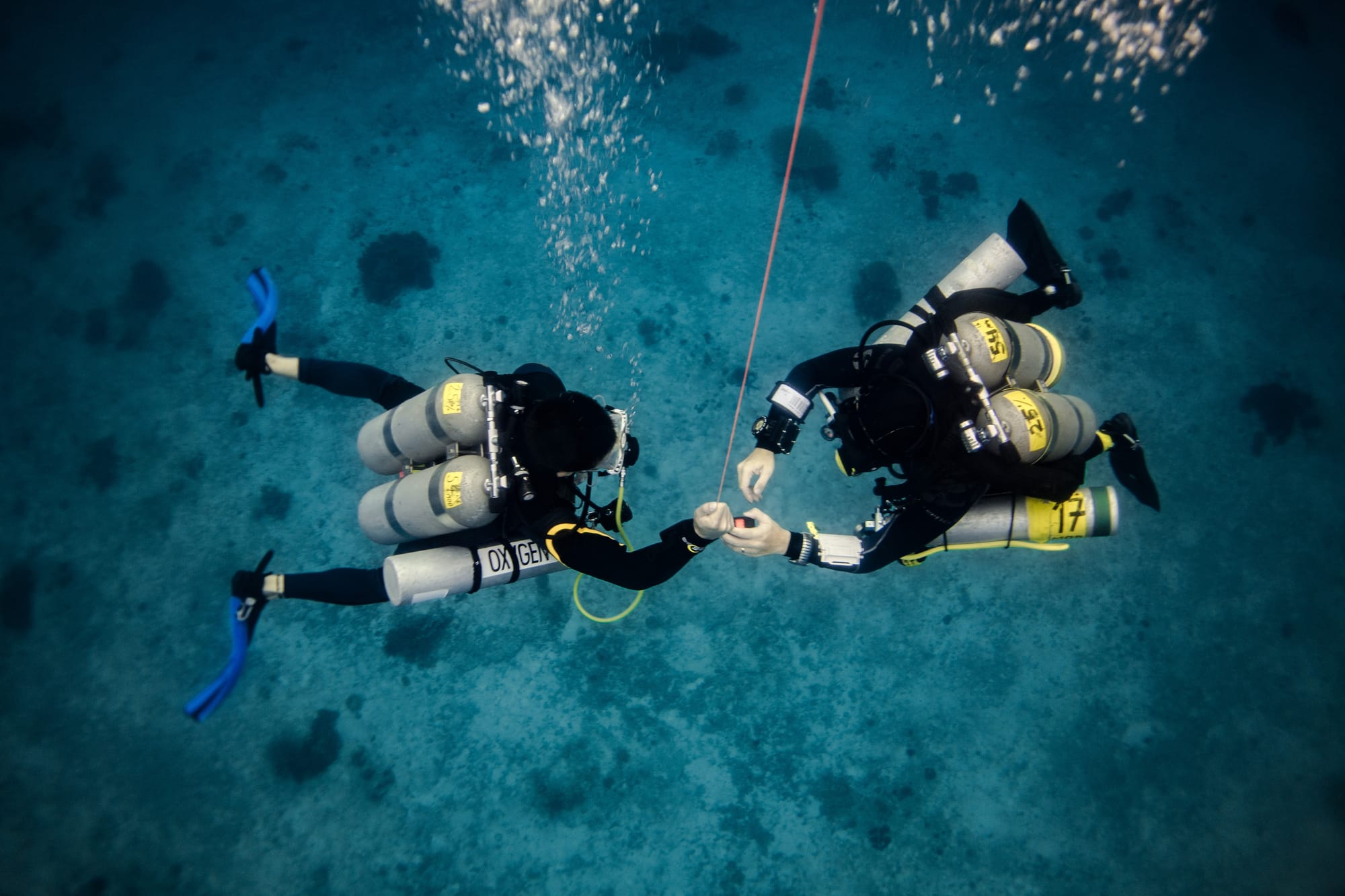 technical scuba divers holding a reel, performing a decompression stop