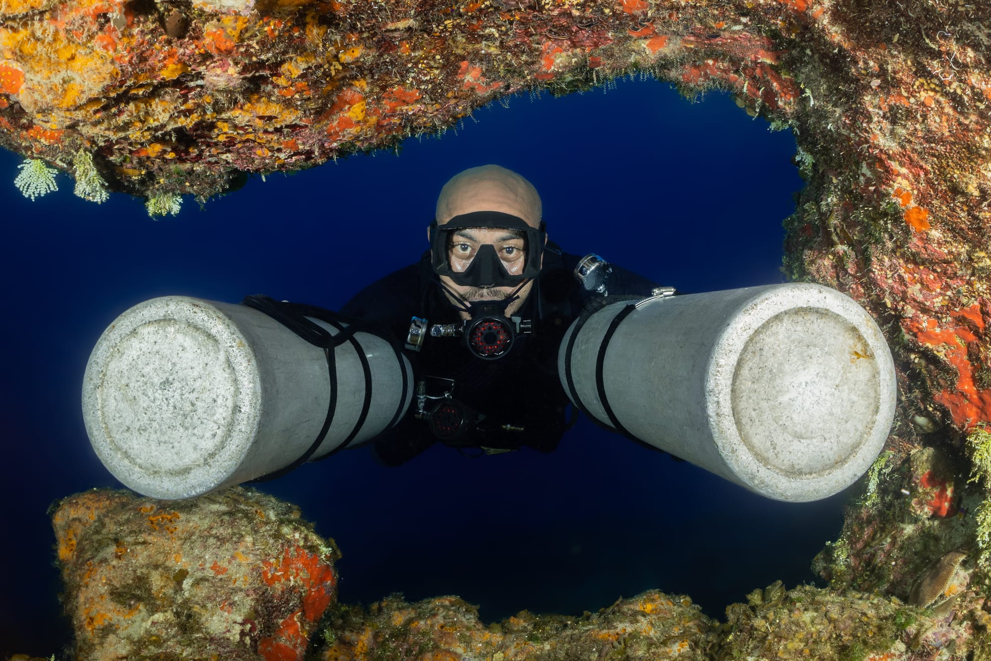 A scuba-diver in a sidemount configuration pushing his scuba cylinders in front of him