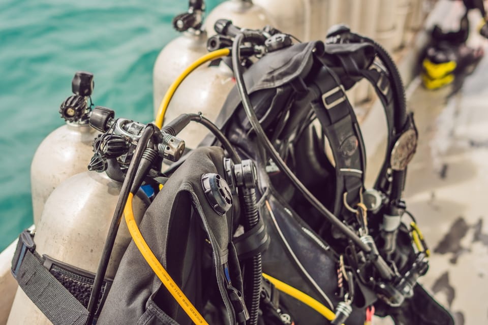 A full scuba unit, tank, BCD and regulator set up next to the water
